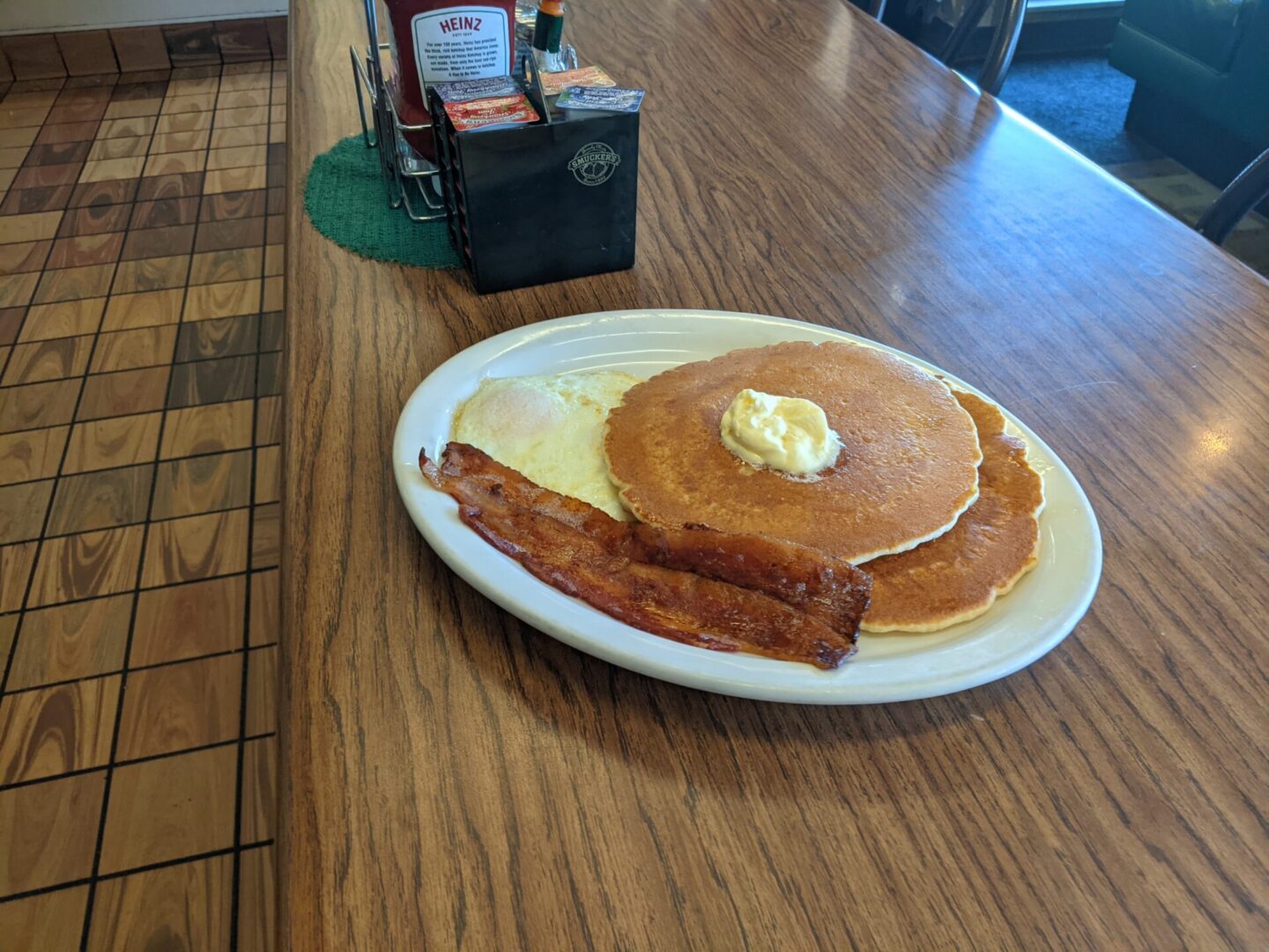 A white plate topped with pancakes and bacon.